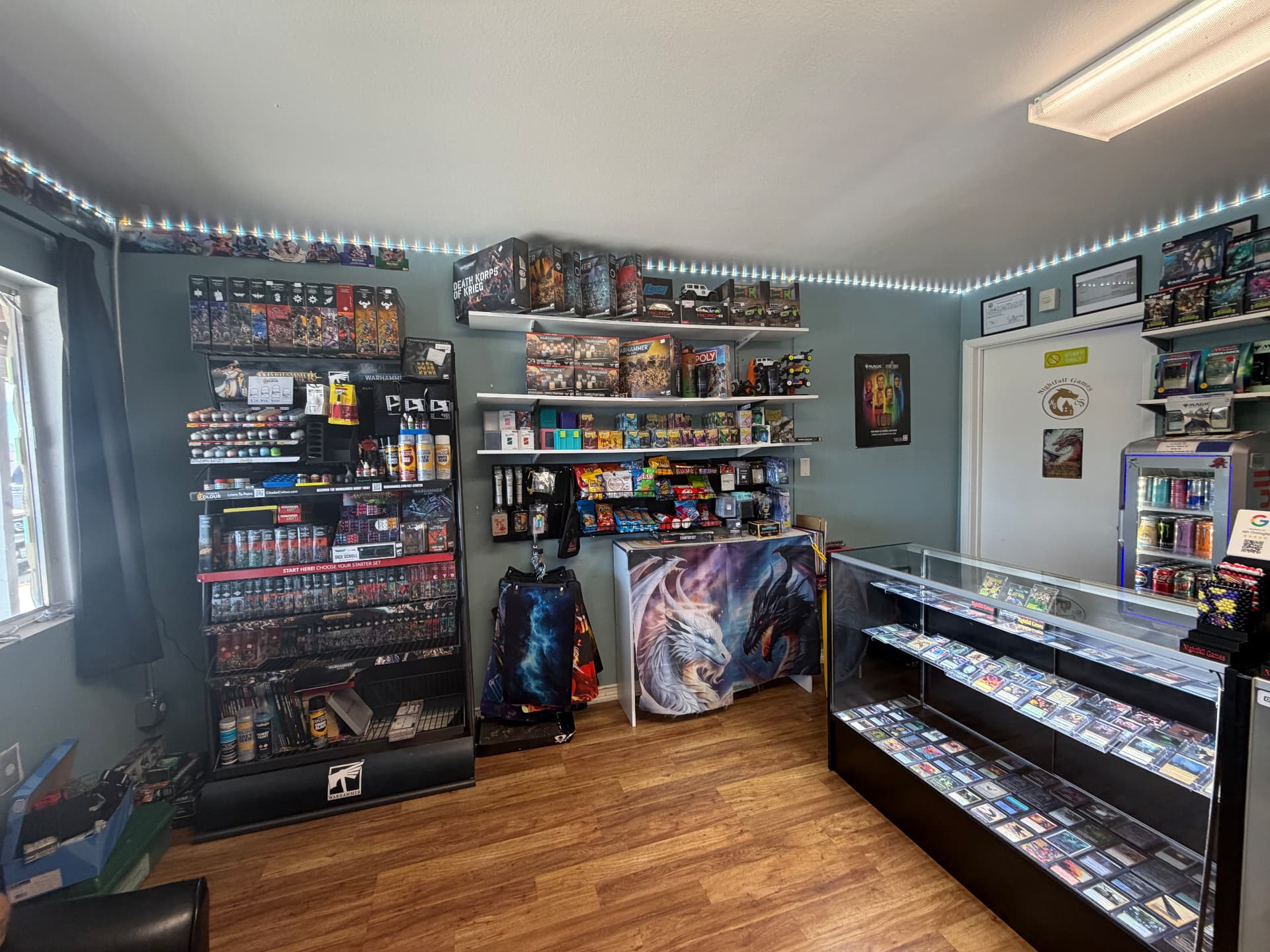 Warhammer paints, boxed kits and RC crawler shelves alongside the Magic singles case and drink cooler at Nightfall Games™