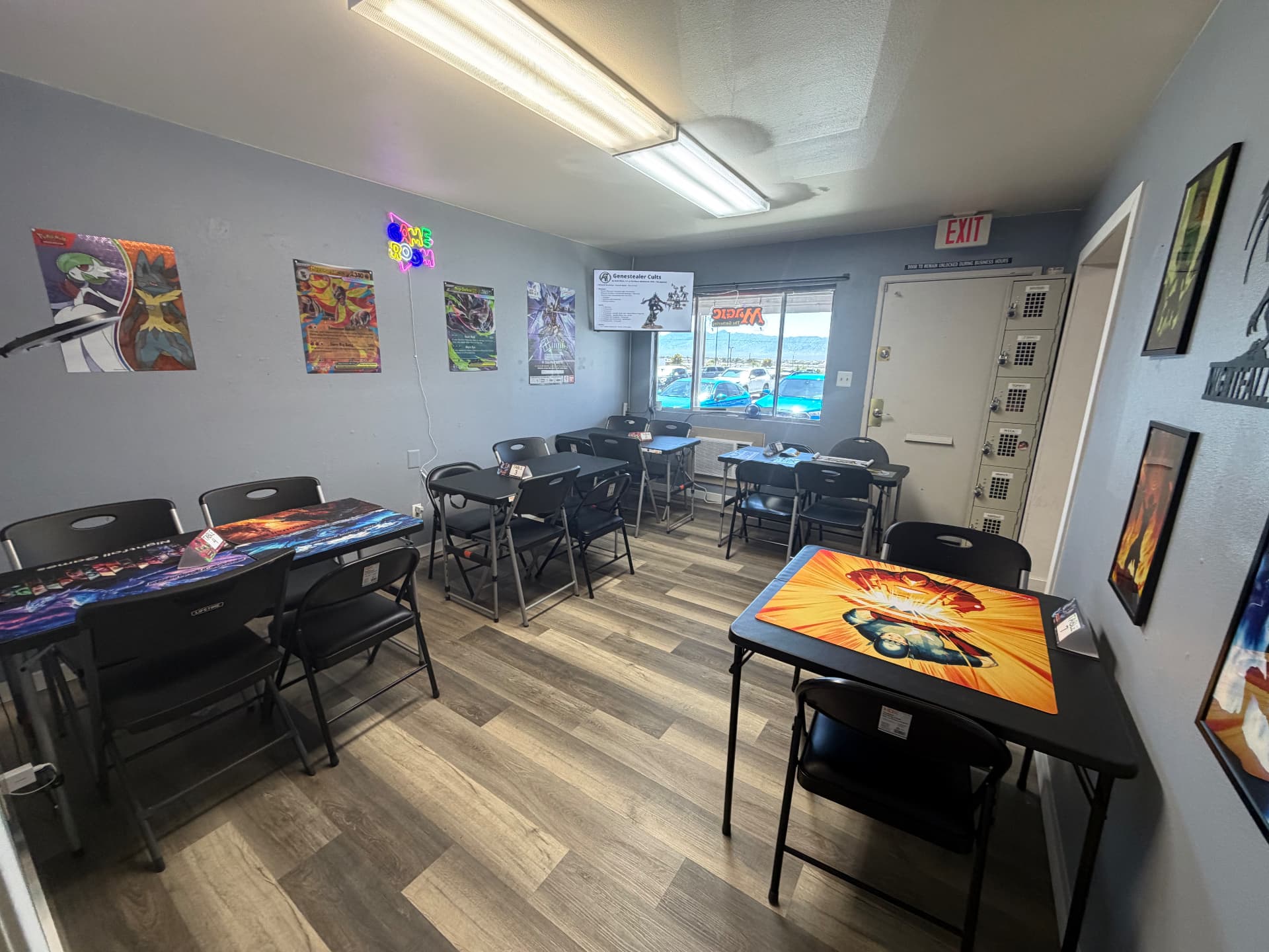 Second angle of the Nightfall Games™ game room with playmat-covered tables, player lockers and a window onto NV-160